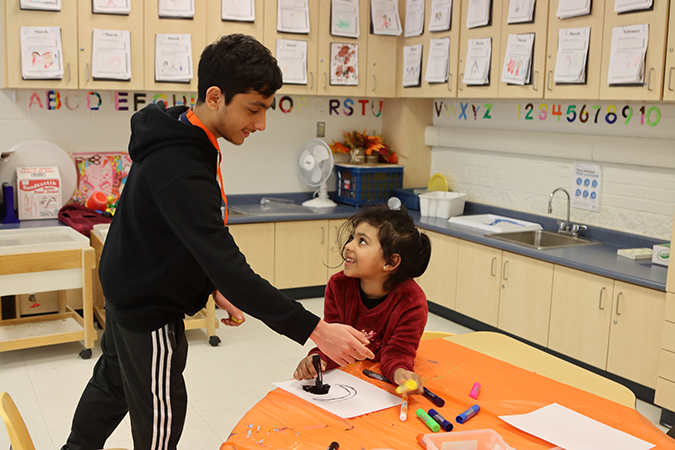 Volunteer passes a marker to a child in program